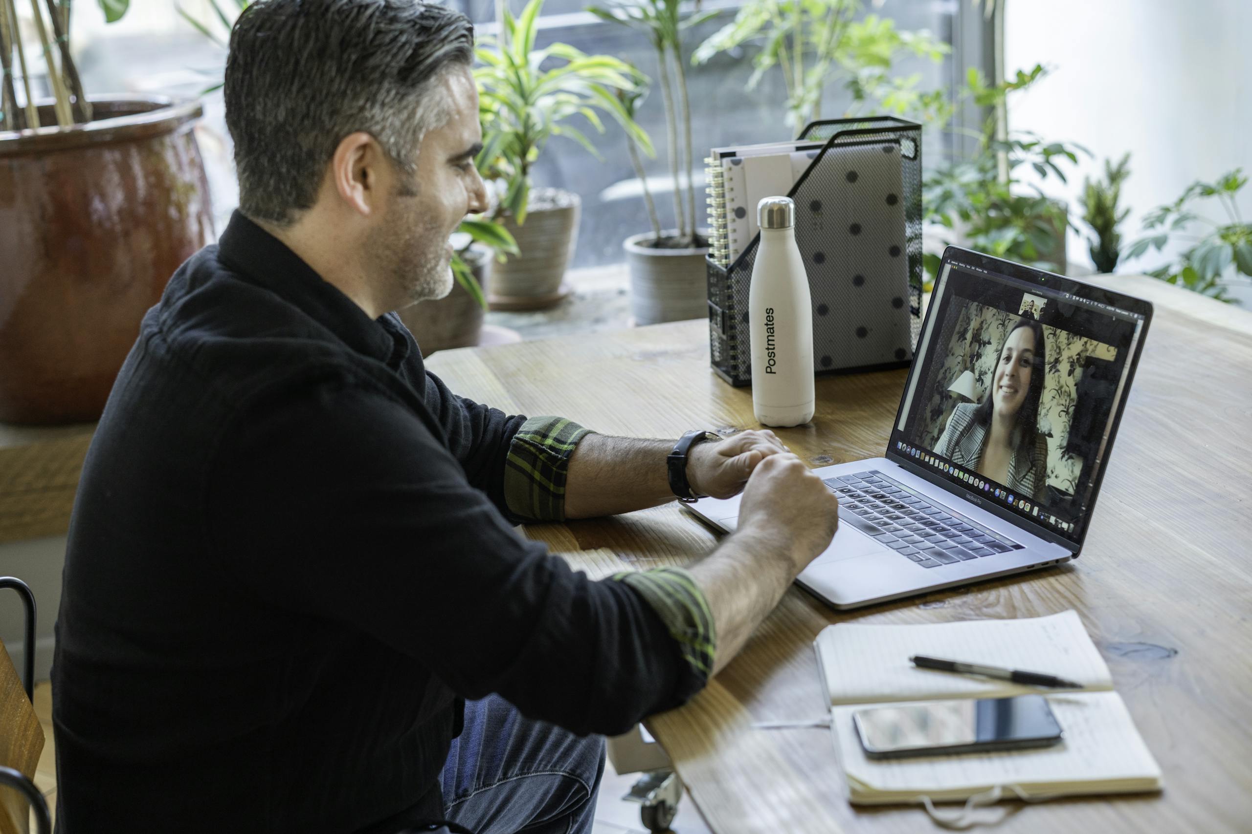 A man participates in a virtual meeting from his home workspace, focusing on remote work.